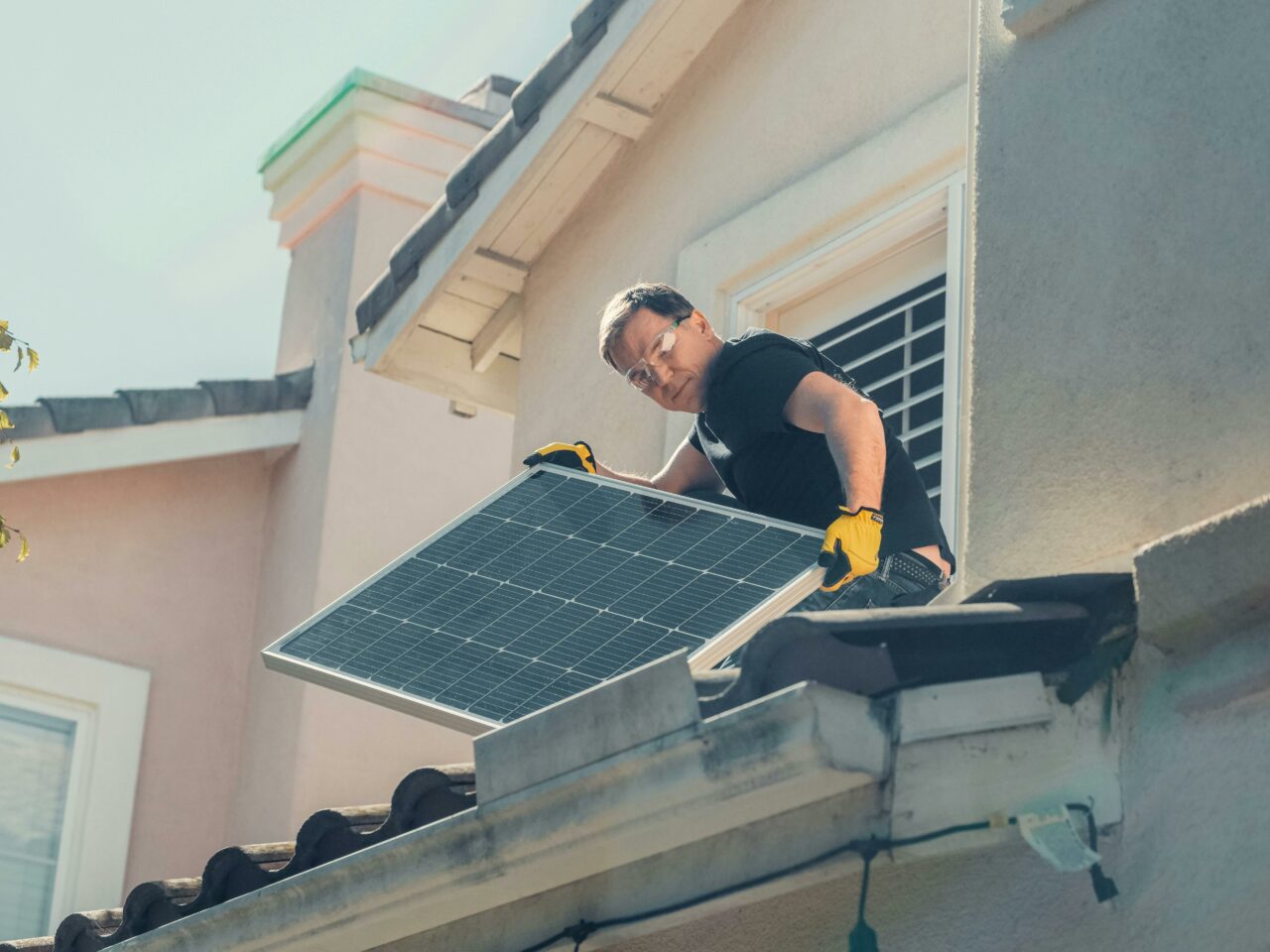 Man with a solar panel on a roof