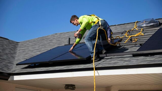 Man on roof with solar panel